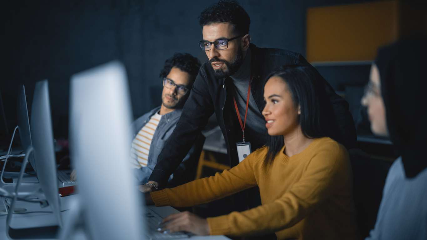 Benefits of outsourcing - Diverse group of software developers working on computers in an office.