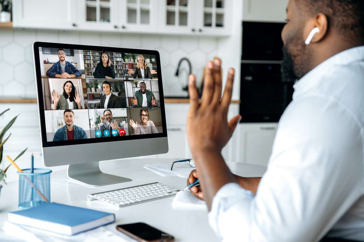 Remote work concept - Man at home having a meeting with his colleagues using a computer.