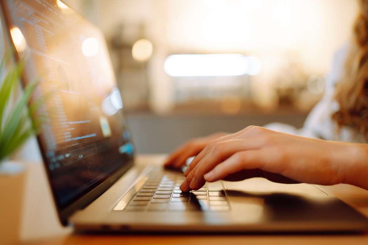 Woman using a laptop while working at home - remote work concept.