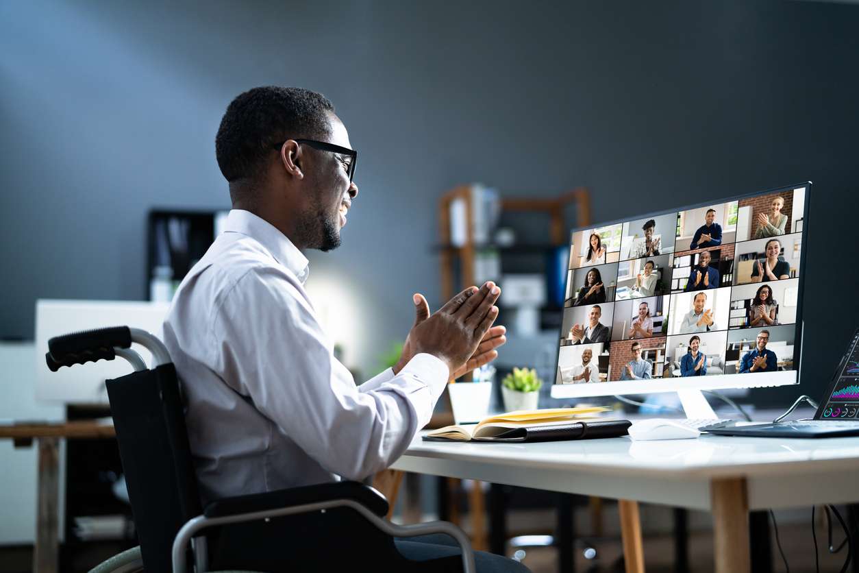 Man in a wheelchair working in a remote work set up - having a video conference with his colleagues.