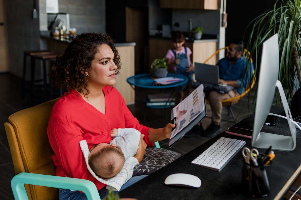 Remote work setup - Mother holding her baby while working at home.