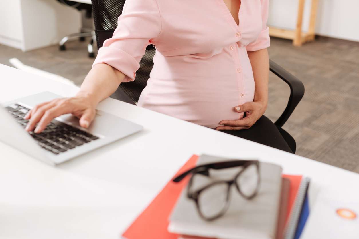 Granting maternity leaves for your pregnant employees. • BrightR Pregnant employee working in an office.