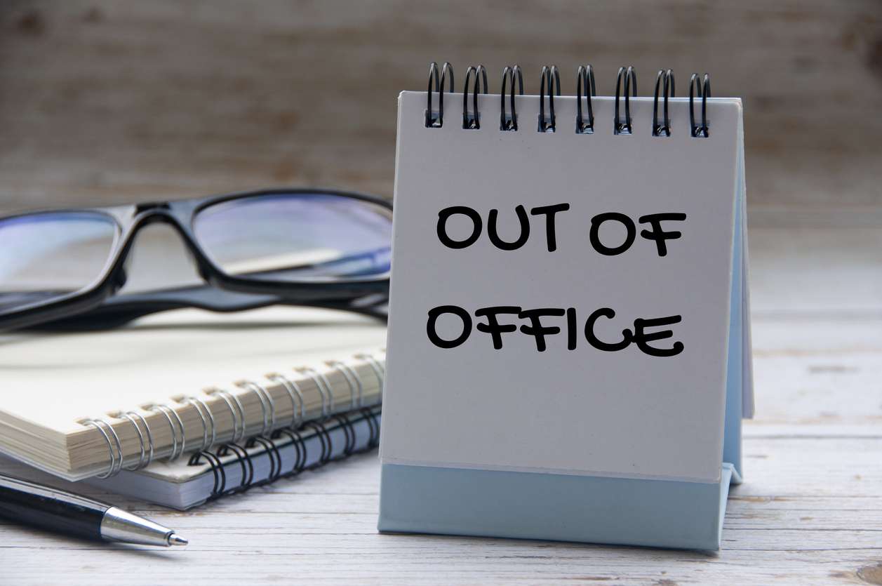Out of office text on a notepad - employee leaves concept.
