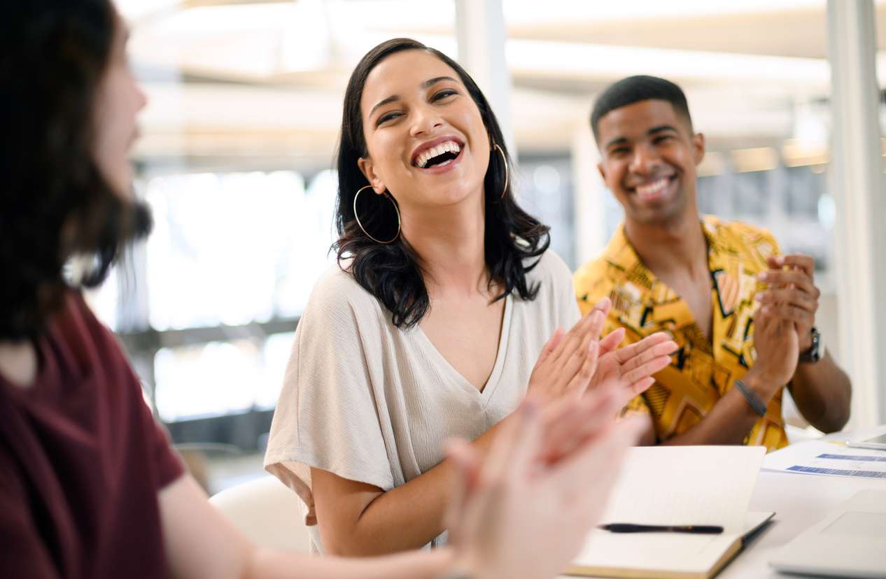 Retaining top talents - A young female employee clapping during their company's employee recognition.