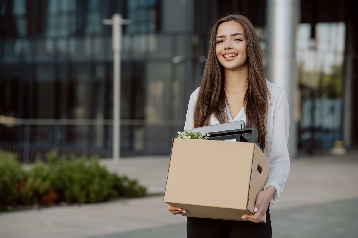 Woman holding a box with packed things following retention policies.