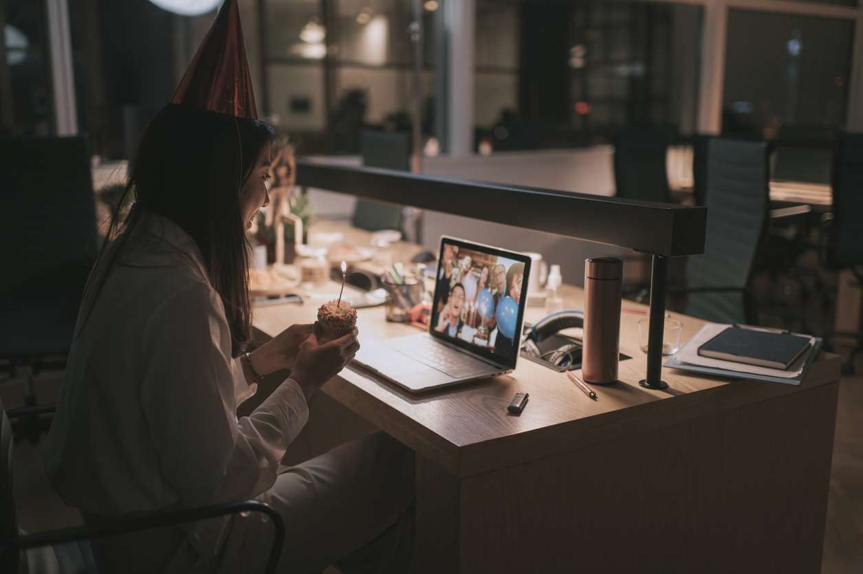 Celebrating with your remote employees. • BrightR A female remote employee celebrating her birthday with her colleagues through a video call.