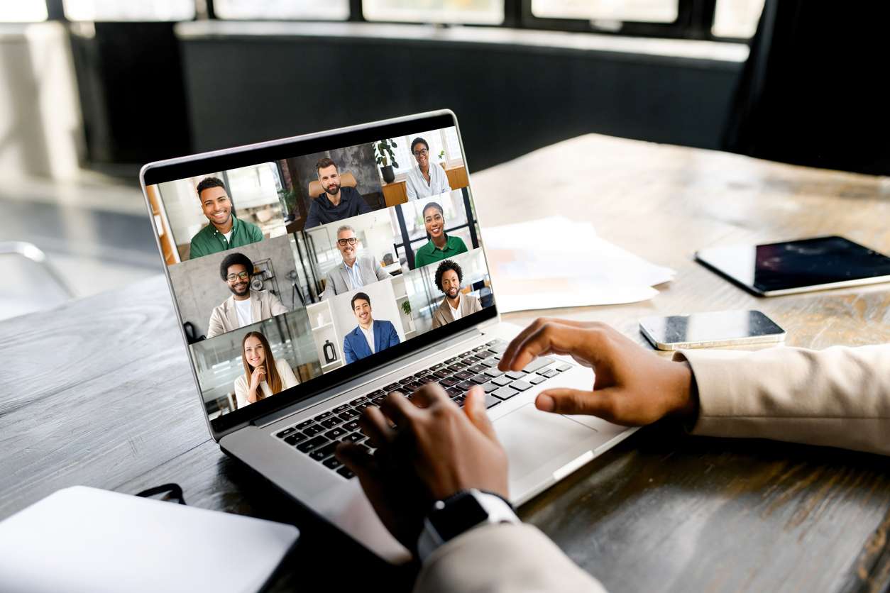 Global workforce management - A businessman using a laptop while having a virtual meeting with his employees.
