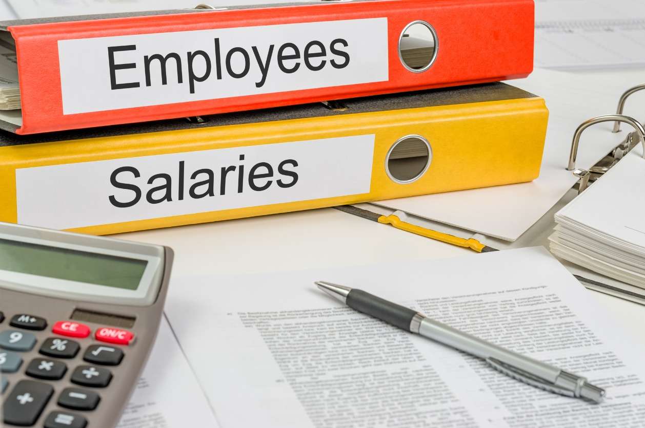 Global workforce management - Employee payroll documents on a table with a calculator.