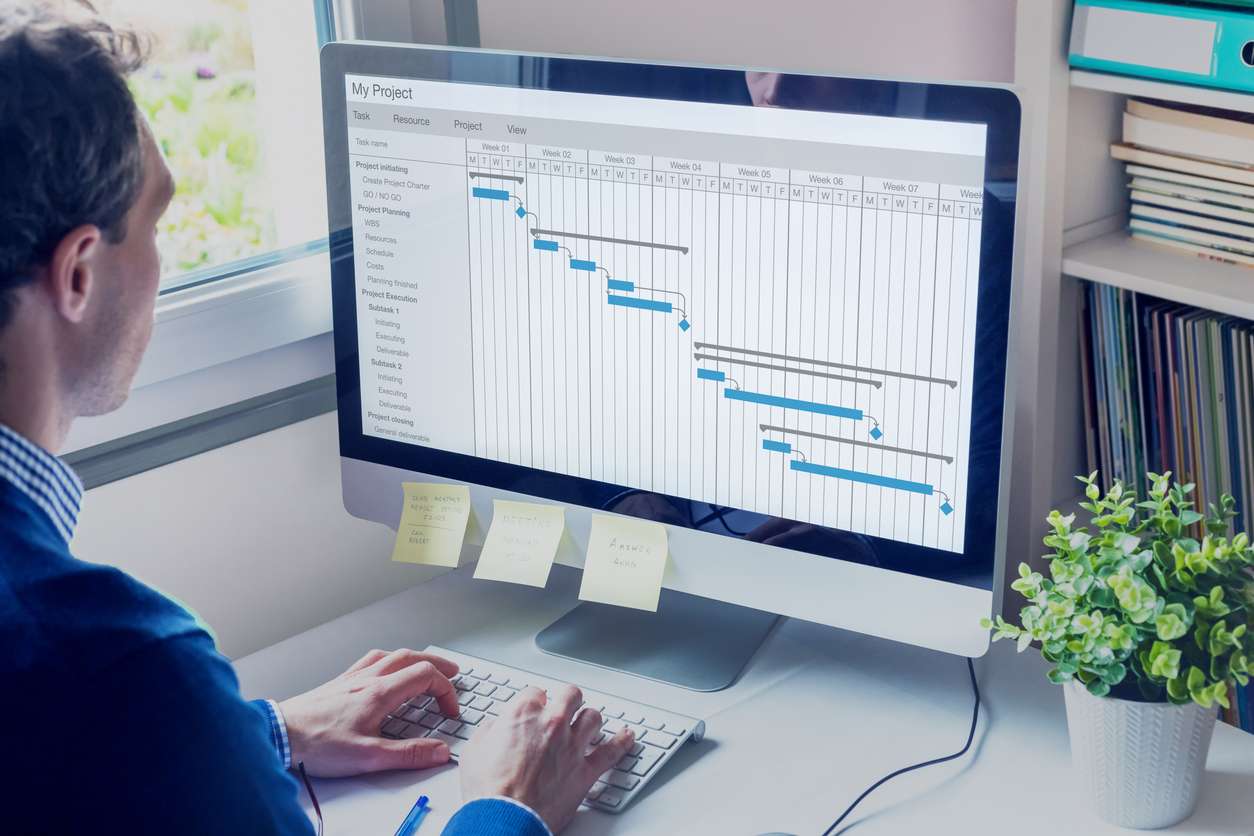 Scheduling for global workforce management - A businessman using a computer showing the use of project management software.