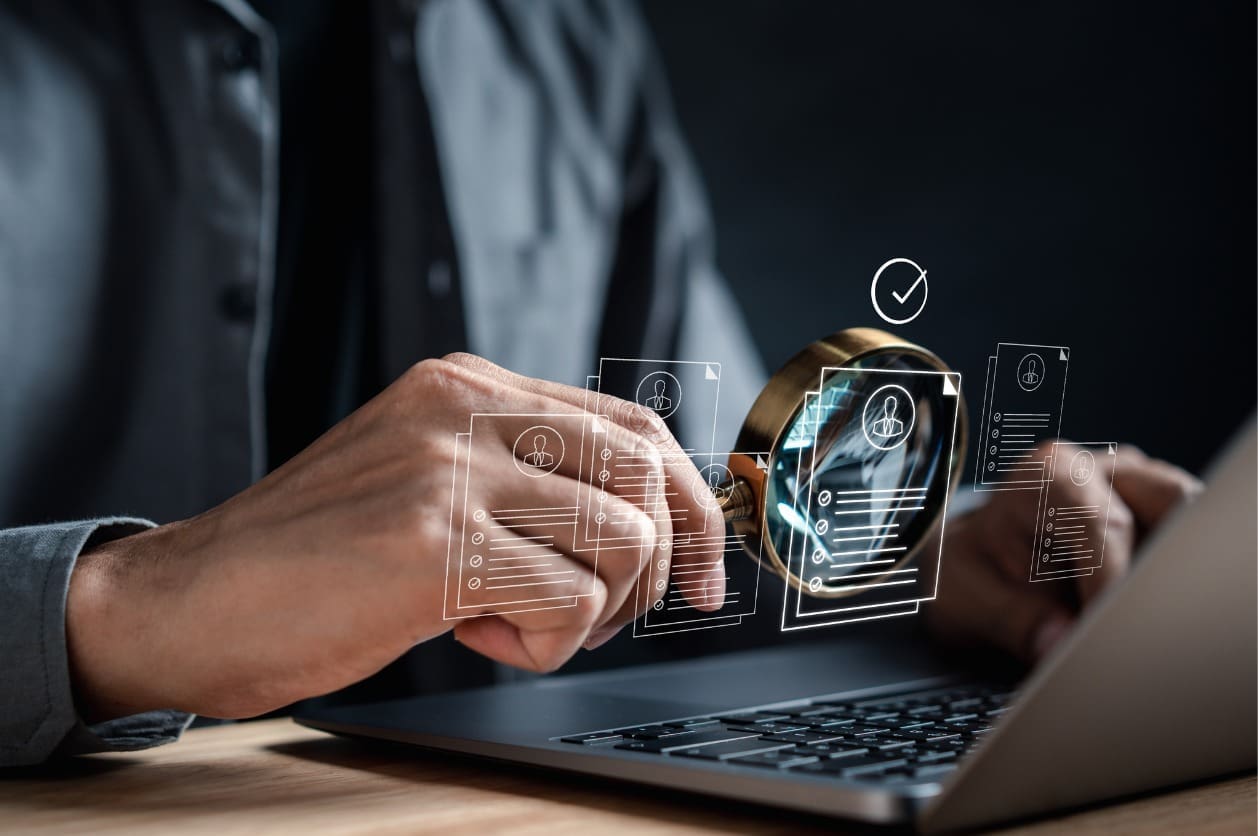 Improving your hiring process through AI - A male employer using AI tools on a laptop to review candidate resumes.