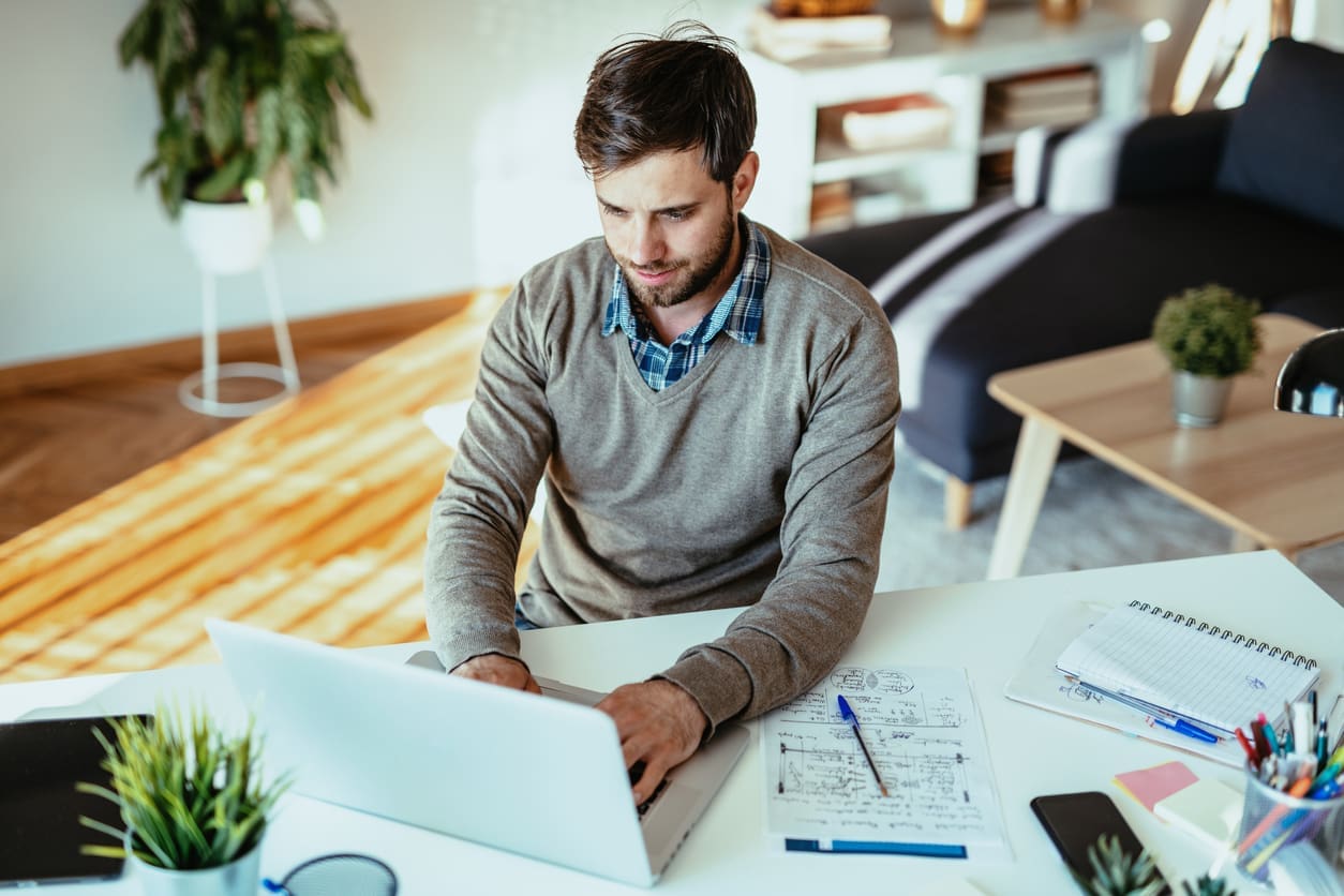 Assessing remote team success - A man using a laptop while working at home.