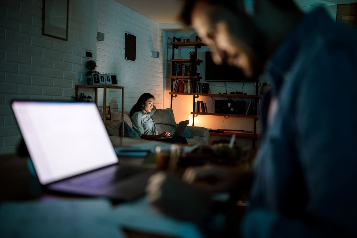 Improving time zone communication strategies - A couple at home using their laptops while working on their tasks.