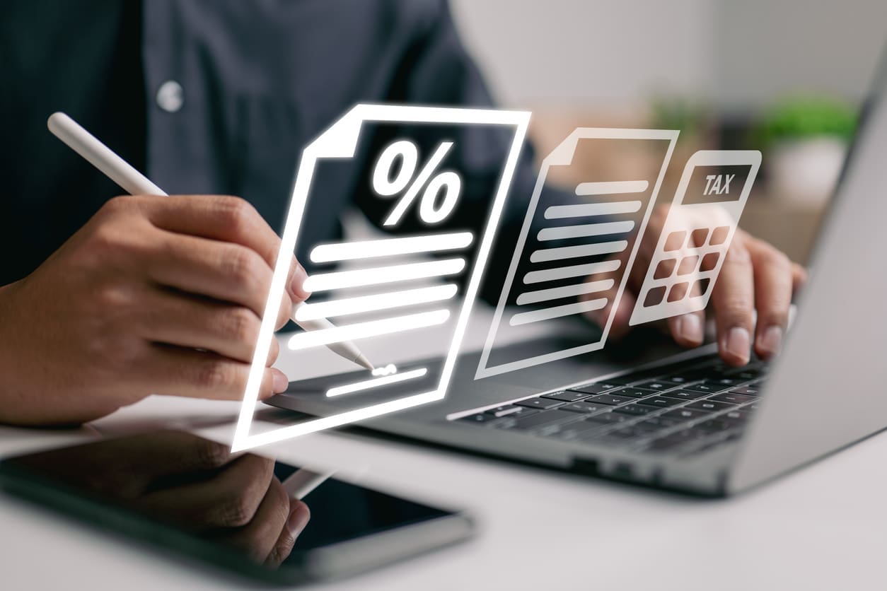 EOR risk mitigation - A businessman using a laptop while reviewing payroll and tax code compliance.