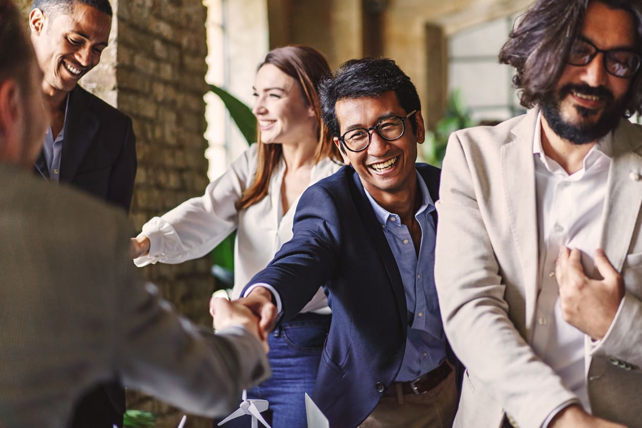 Cross-border recruitment - A diverse group of newly hired employees shaking hands with their employers.