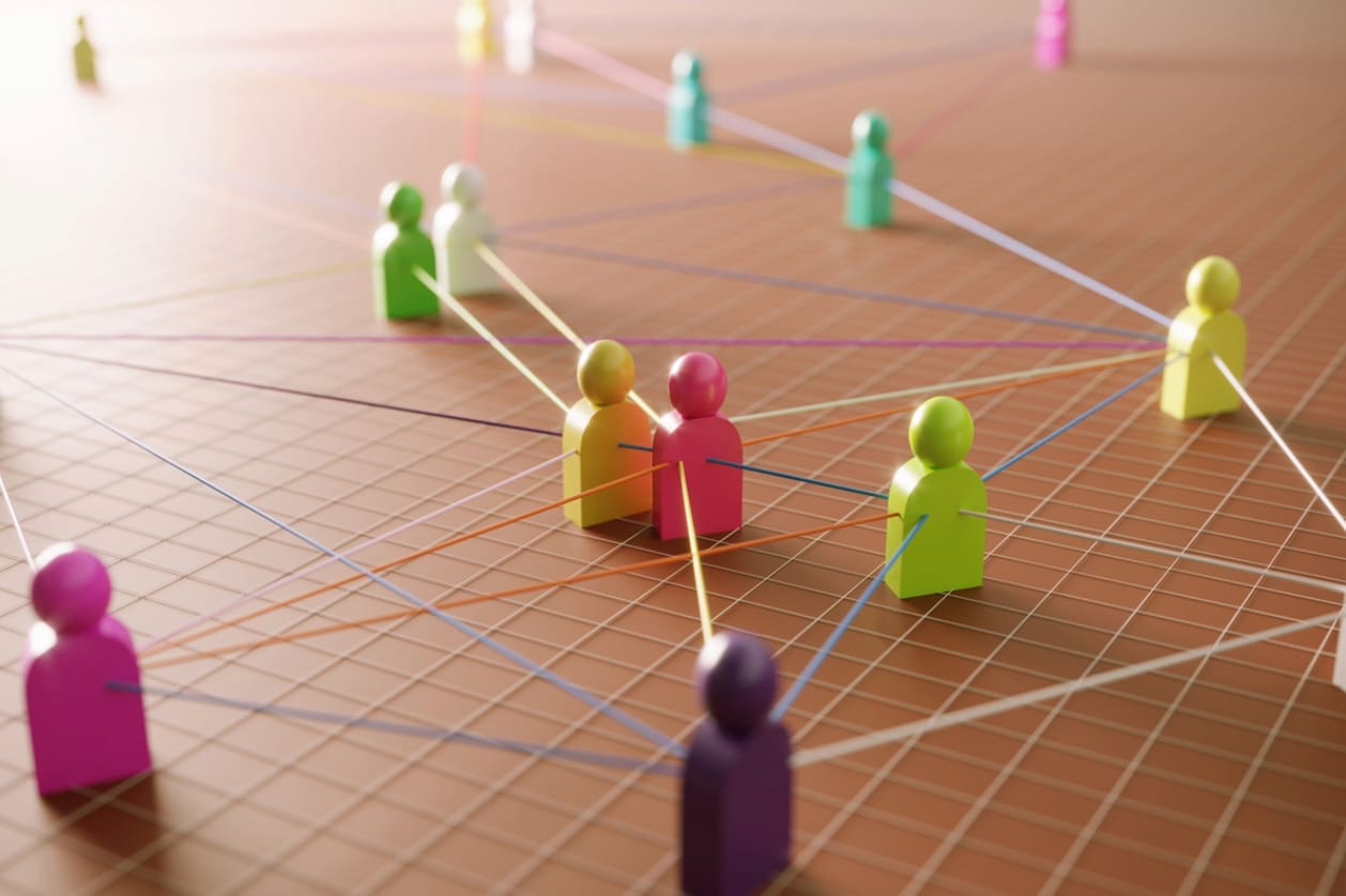 Building international teams - Multicolored human figures connected to each other through strings.