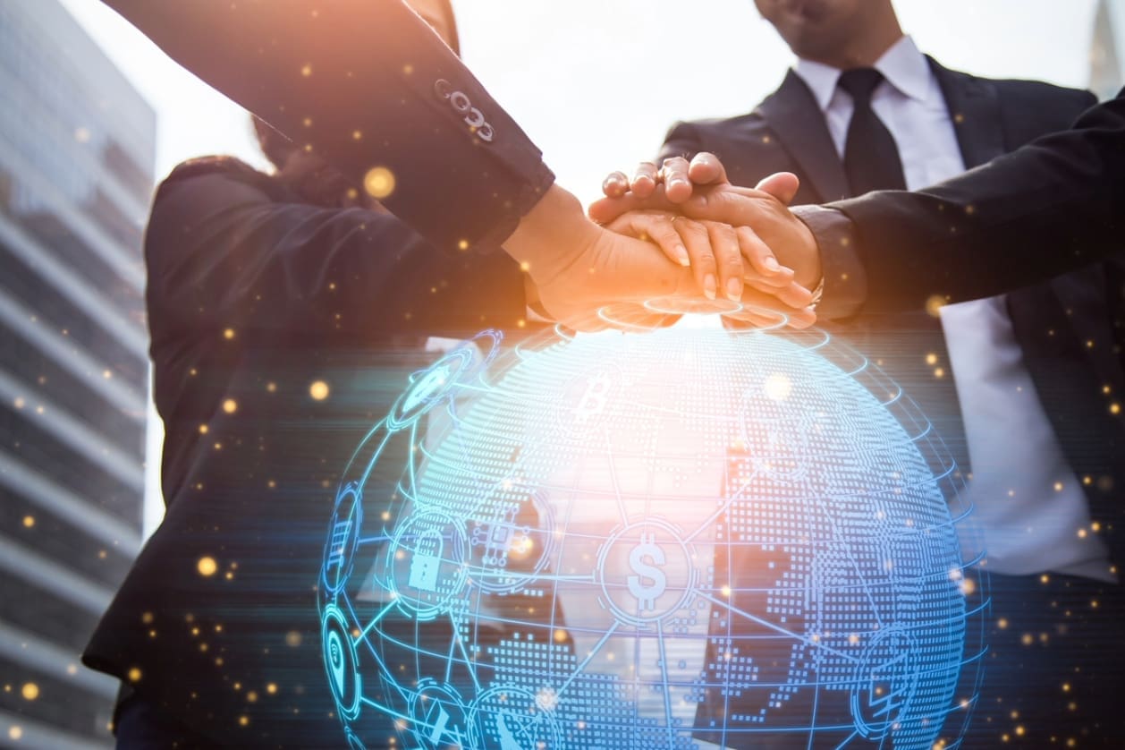 International business expansion - A diverse group of employees putting their hands over a digital globe.
