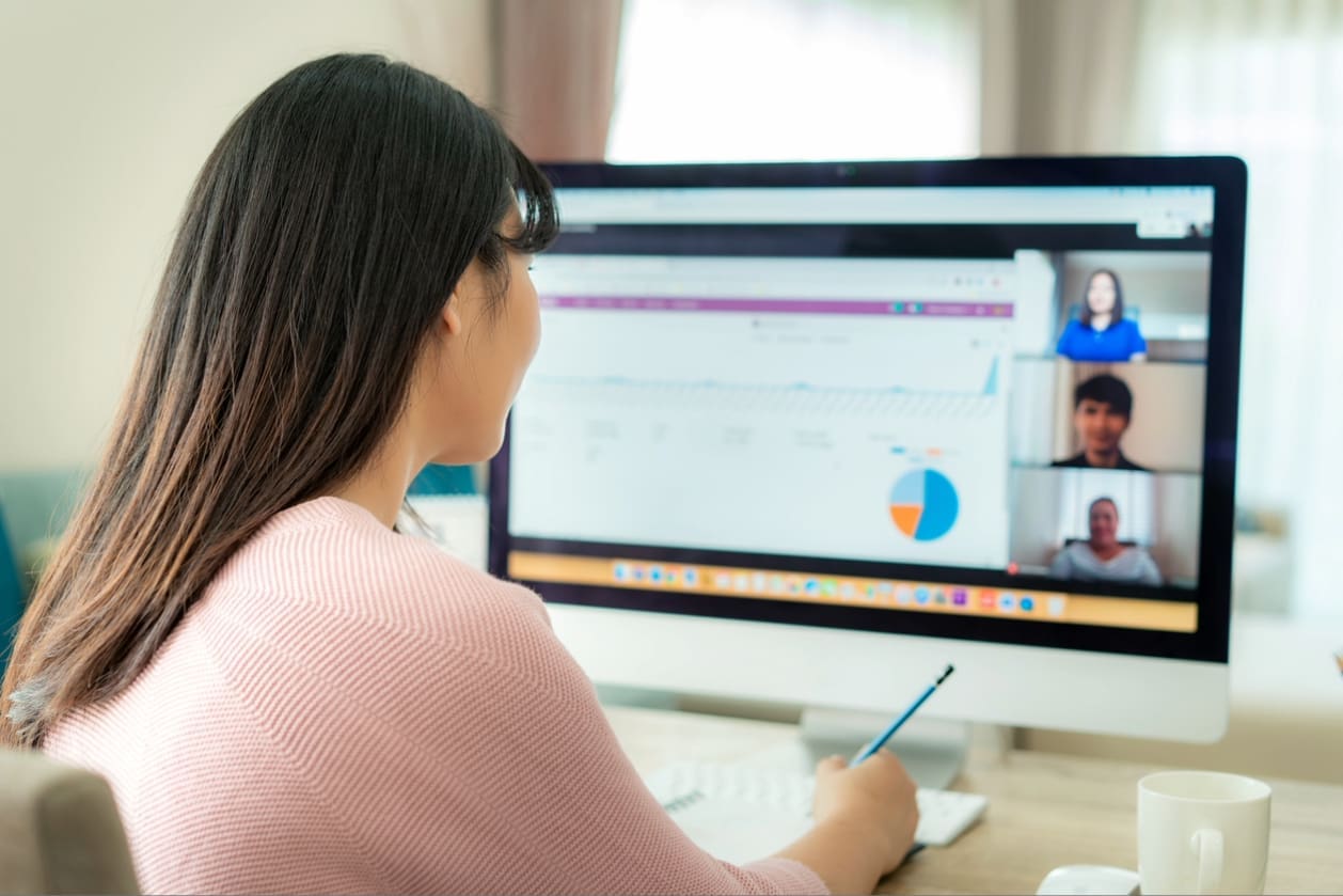 Global remote teams - A woman at home using her computer while doing work tasks with her colleagues.