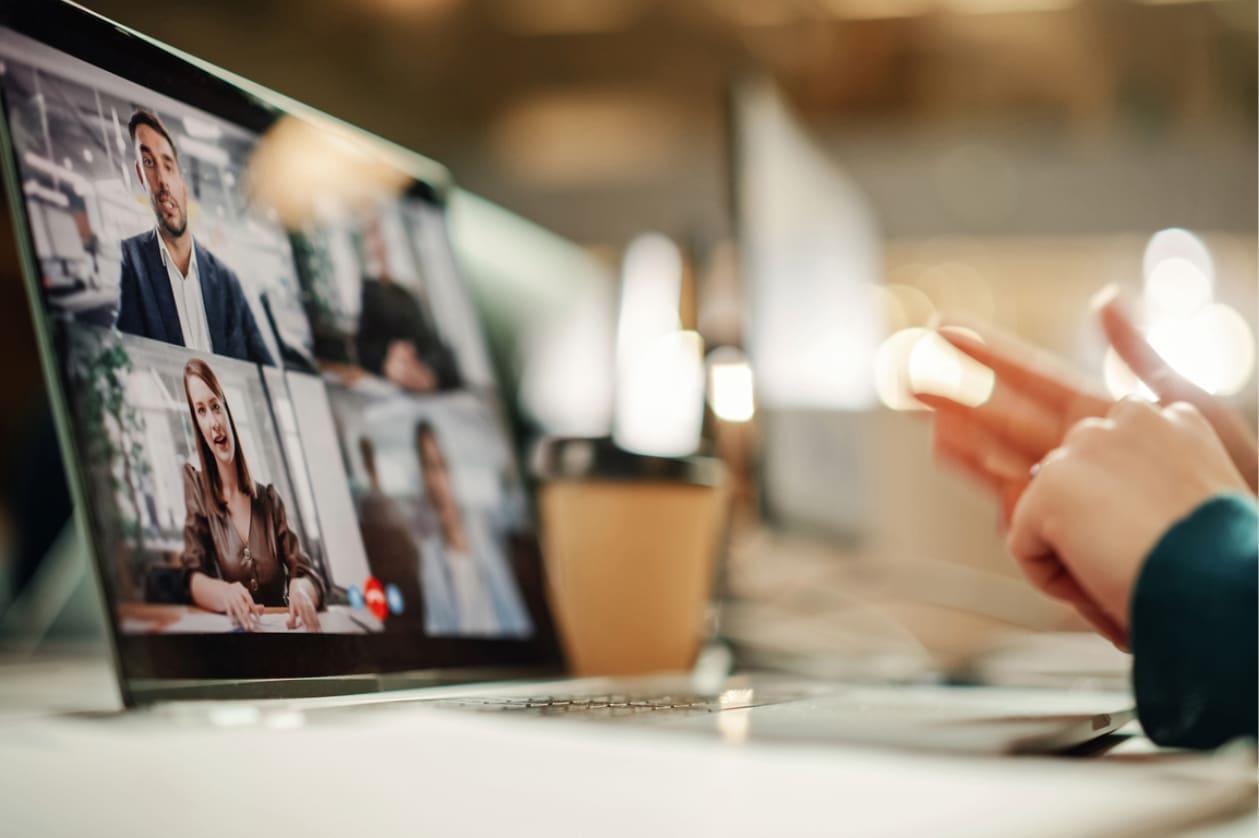 Global remote teams - A laptop screen showing a virtual meeting between a diverse group of employees.