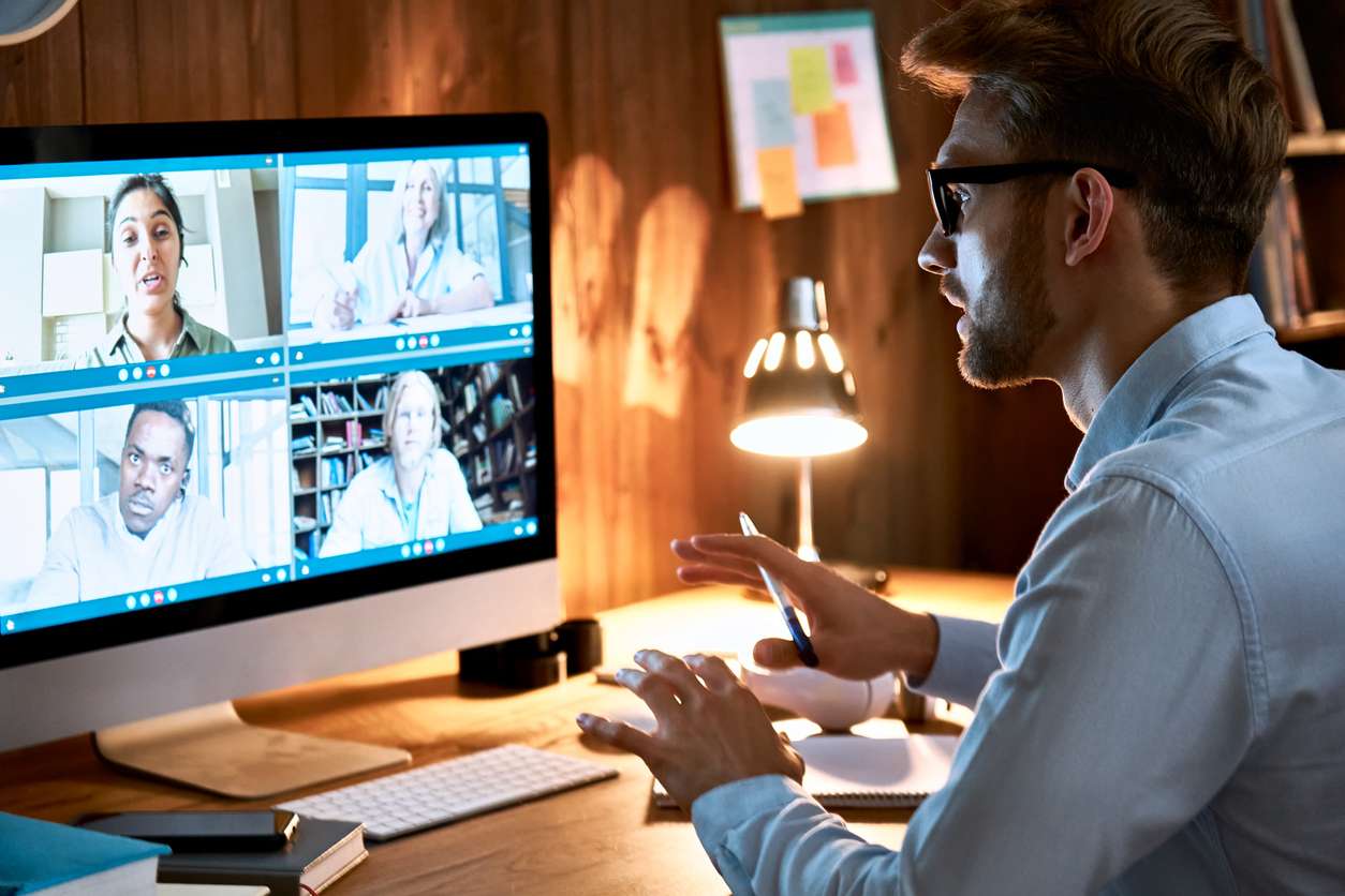 Businessman leading virtual team meeting on video conference call using computer while working from home.