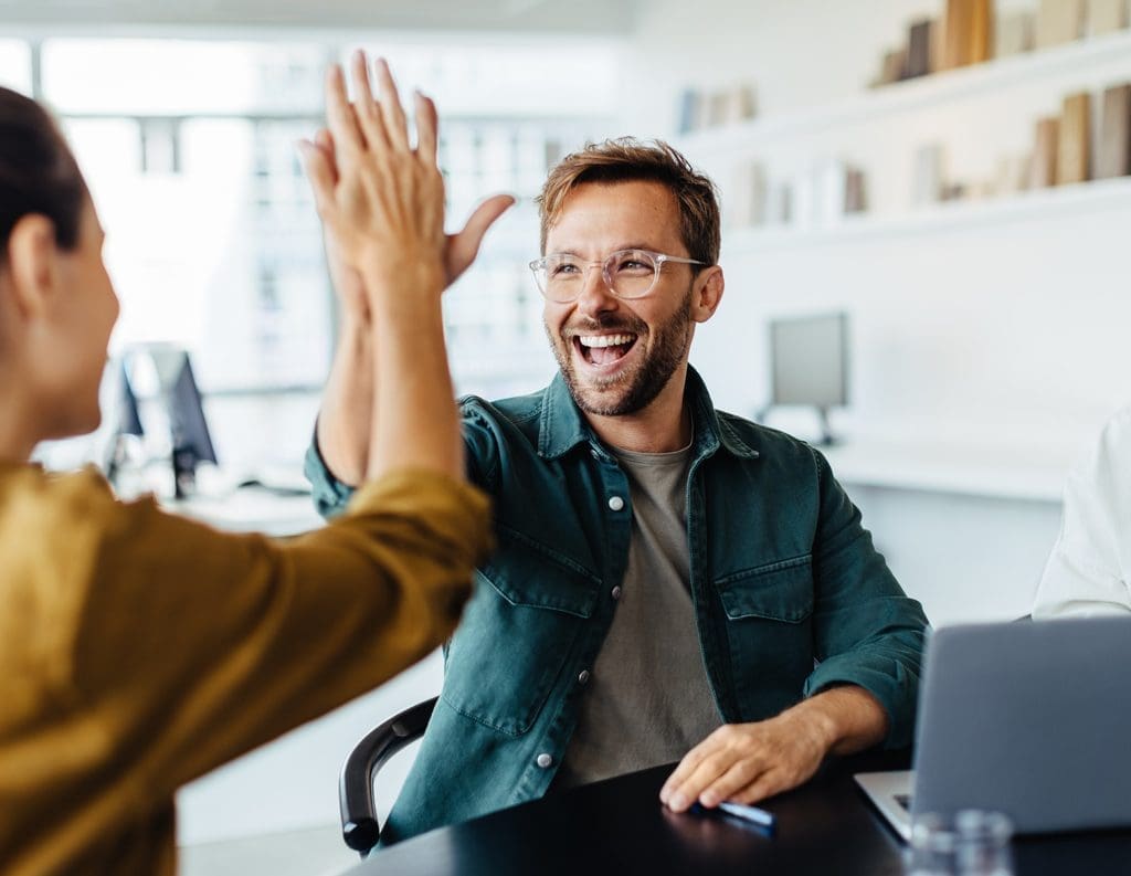 Retention Processes Out-of-Country Staff: Business people celebrating for their success through a high-five.