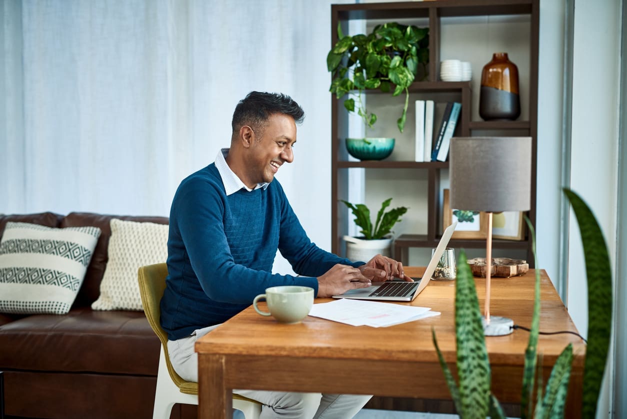 Remote staffing diversity - A male employee at home using a laptop to complete work tasks.