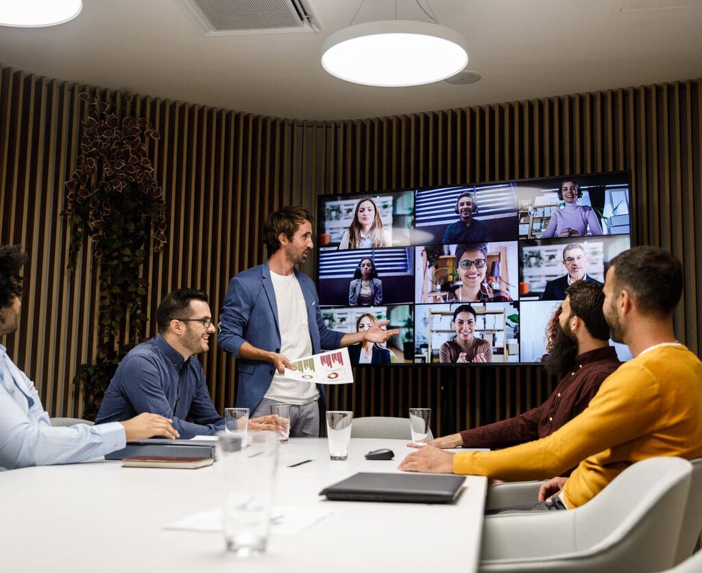 Group of businessmen sitting around a table having a meeting over a video conference.