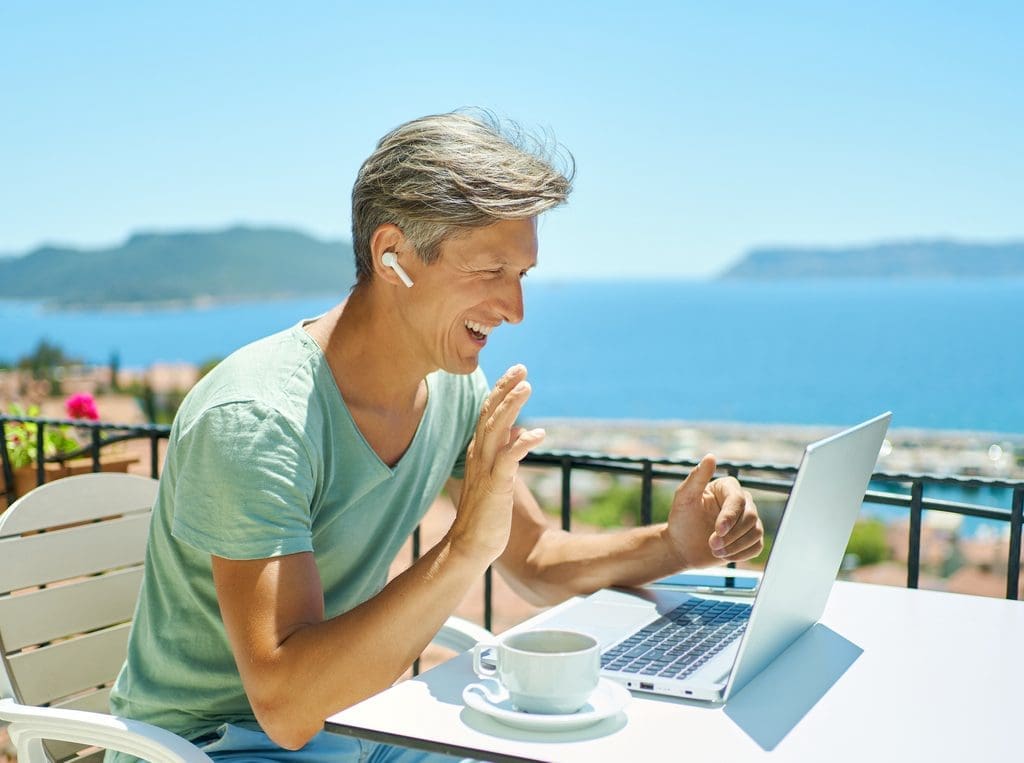 Caucasian male working on laptop while on vacation, depicts using mobile timekeeping tool.