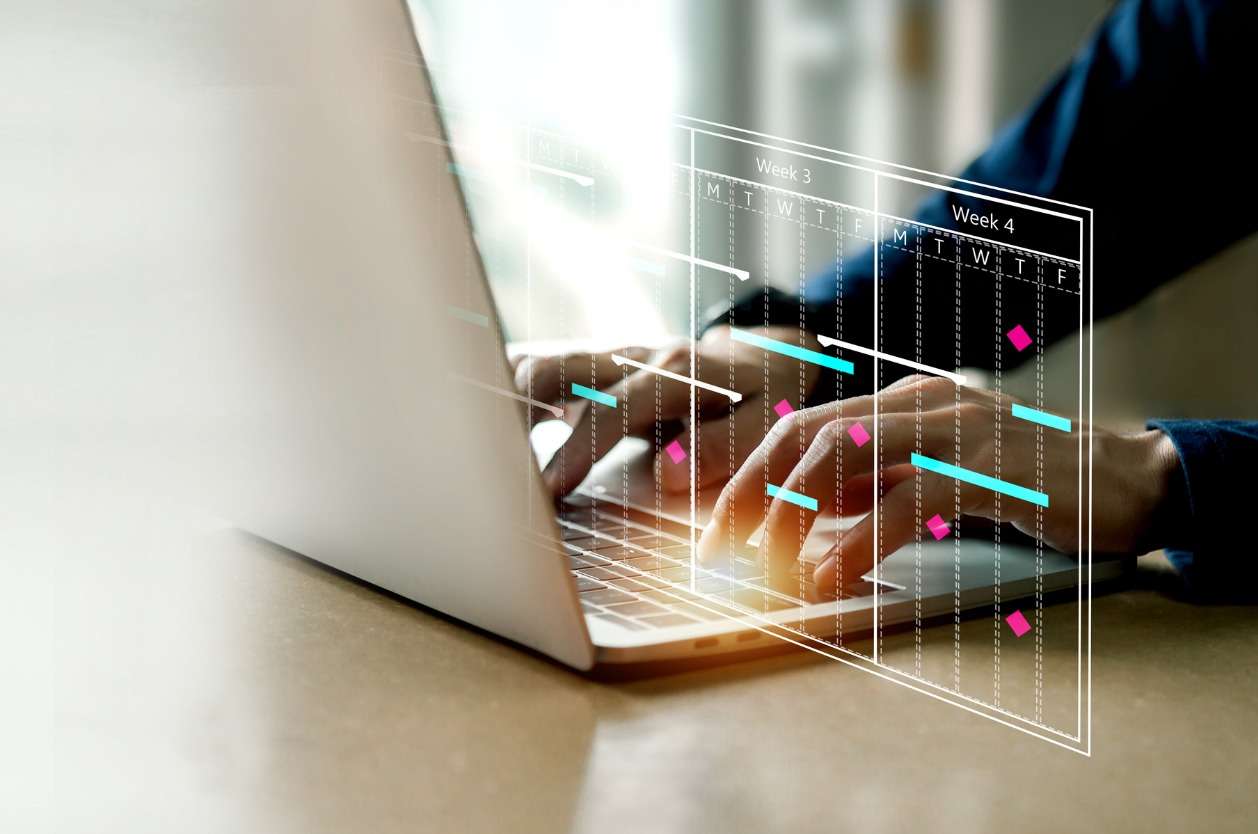 Building off-shift international schedules. • BrightR Improving internal communications with employees - A businessman using a laptop to plot employee schedules.