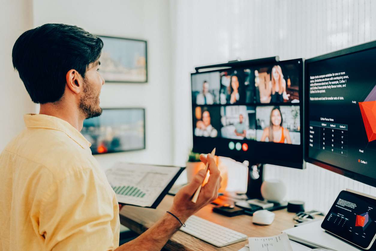 Using performance objectives and KPIs - A businessman using a computer while having a virtual meeting with his employees.