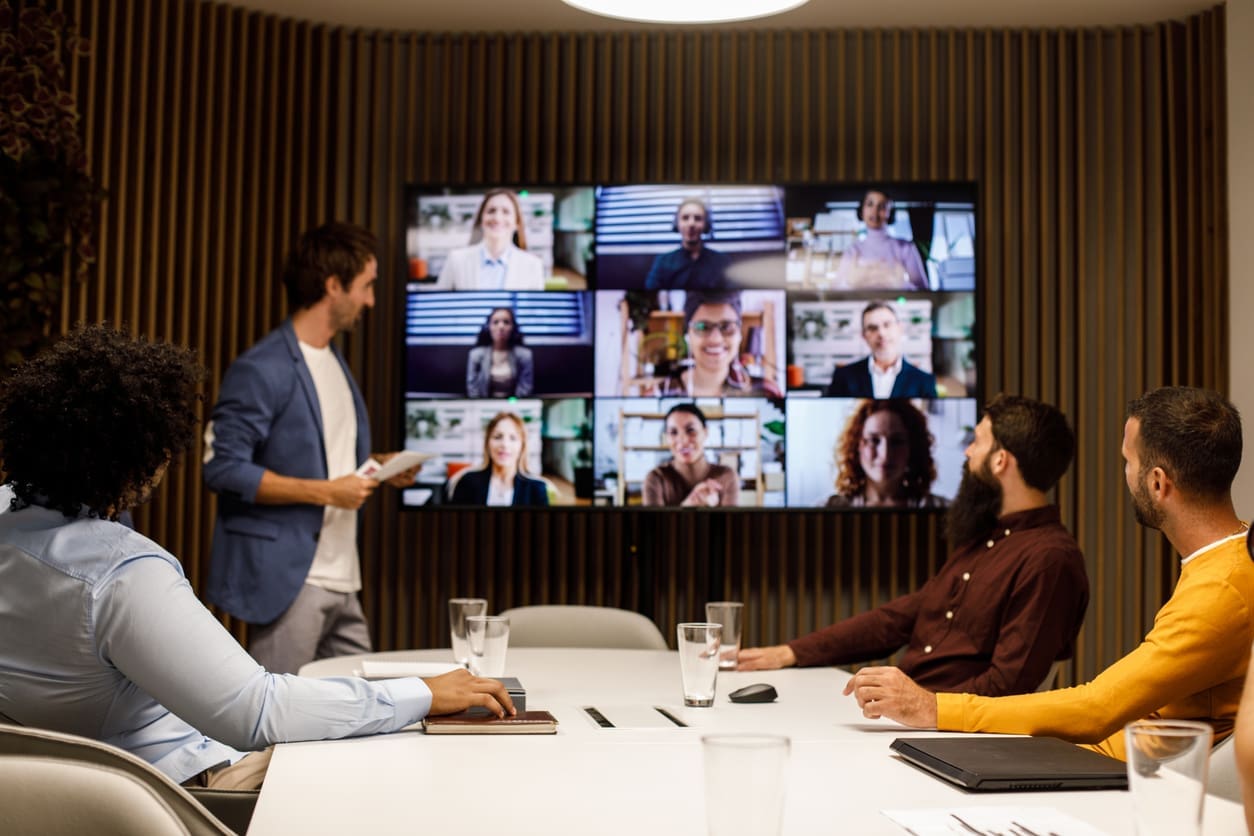 Maintaining communication and connection in the workplace. • BrightR Employee retention strategies - A group of employees in an office having an online meeting with their international colleagues.